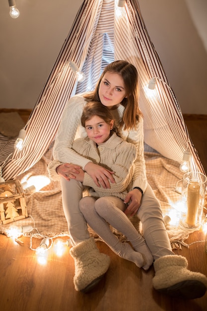 Linda mãe e filha, véspera de Natal, sentadas no interior aconchegante. Ano Novo.