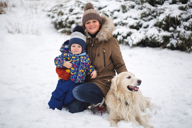 Linda mãe e filho brincando com o cachorro na neve
