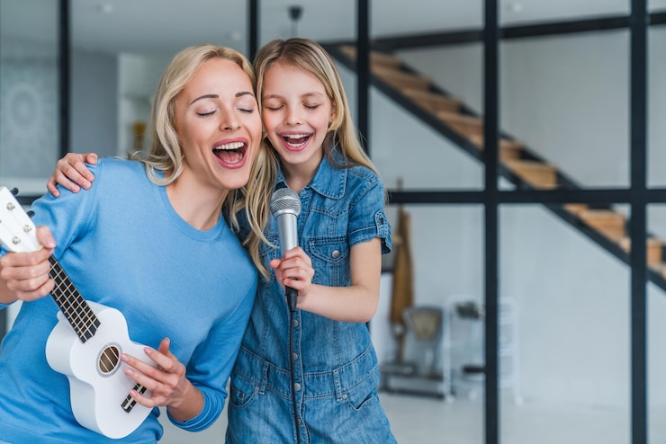 Foto linda mãe e sua filha bonitinha com microfone cantando juntos e tocando ukulele