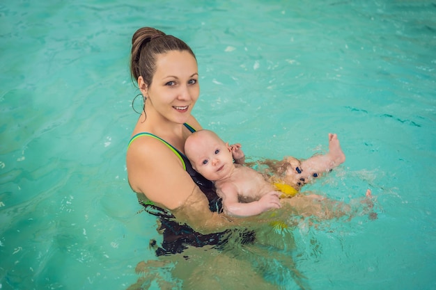 Linda mãe ensinando uma linda garotinha a nadar em uma piscina Criança se divertindo na água com a mãe