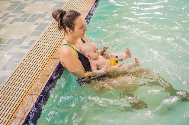 Linda mãe ensinando uma linda garotinha a nadar em uma piscina Criança se divertindo na água com a mãe