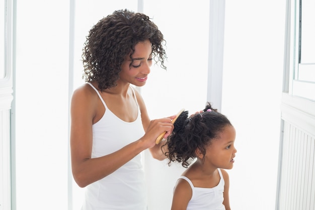 Linda mãe escovando o cabelo de suas filhas