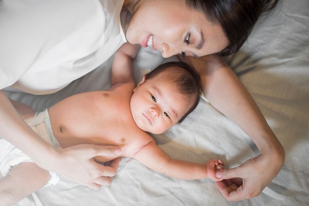 Linda mãe está brincando com seu bebê recém-nascido no quarto.