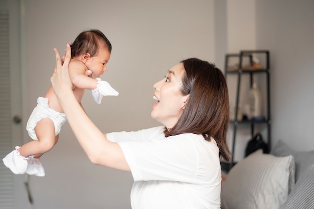 Linda mãe está brincando com seu bebê recém-nascido no quarto.