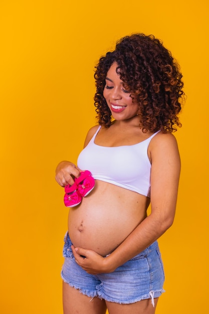 Linda mãe grávida com chinelo rosa em fundo amarelo