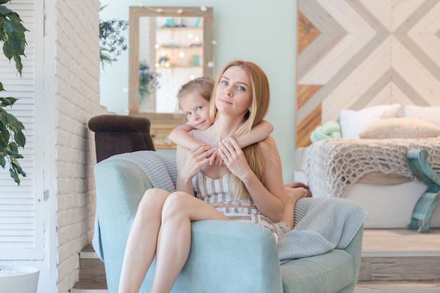 Linda mãe loira e linda filha se divertindo e brincando em um apartamento moderno com um design elegante