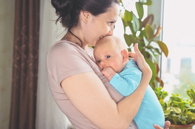 Linda mãe segurando nos braços seu lindo filho recém-nascido. Expressões faciais de bebê