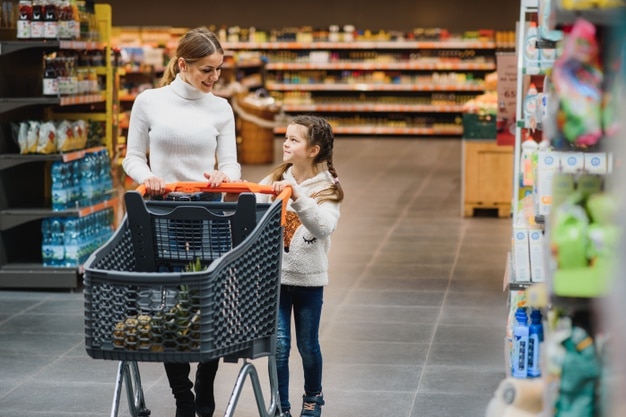 Linda mãe segurando uma cesta de supermercado com o filho caminhando no supermercado