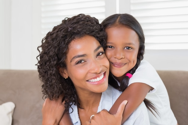 Foto linda mãe sentada no sofá com a filha sorrindo para a câmera