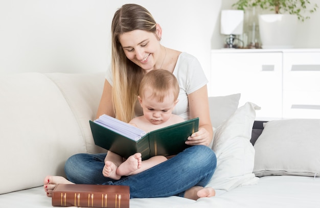 Linda mãe sorridente lendo história para seu filho de 9 meses