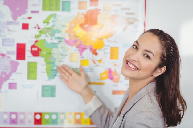 Foto linda maestra mostrando el mapa del mundo en un aula