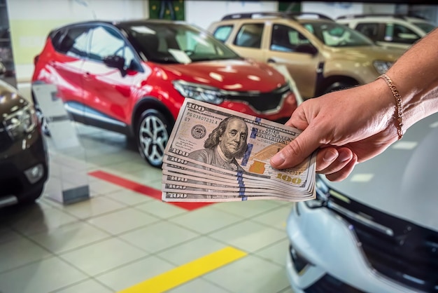 Linda mão limpa e saudável segura firmemente uma soma redonda de notas de dólar no carro