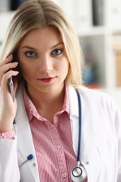 Linda médica loira falando ao telefone