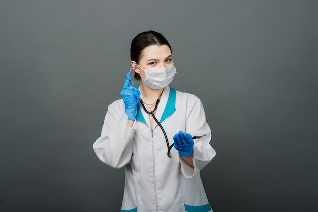 Linda médica na máscara protetora, olhando para longe e pensando em algo.