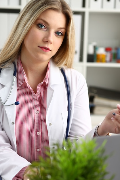 Linda médica sorridente sente-se no local de trabalho