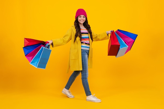 Linda menina adolescente de moda com sacolas de compras em fundo amarelo Compras viciadas em compras