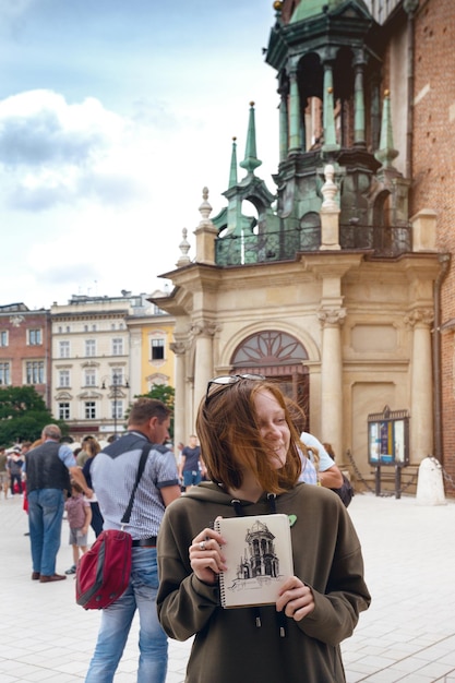 Linda menina adolescente sentar e pintar na praça. Wroclaw, Polônia