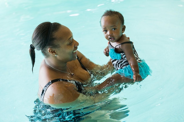 Linda menina aprendendo a nadar na piscina coberta.