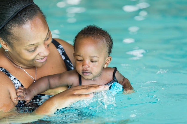 Linda menina aprendendo a nadar na piscina coberta.