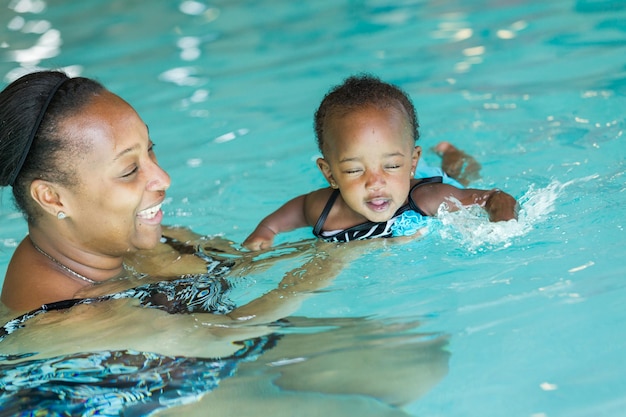 Linda menina aprendendo a nadar na piscina coberta.