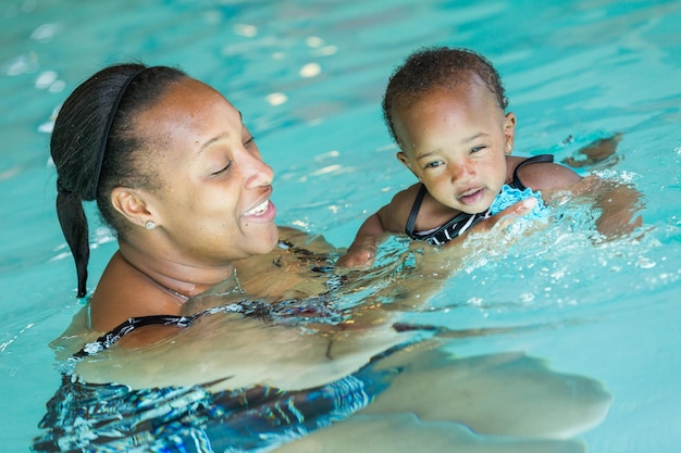 Linda menina aprendendo a nadar na piscina coberta.