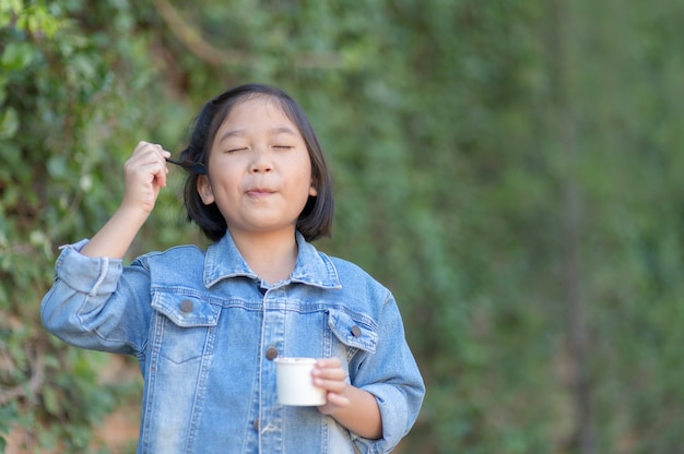 linda menina asiática usar jaqueta jeans desfrutar de comer sorvete no fundo da natureza, conceito de estilo de vida e