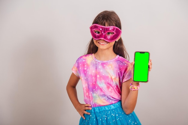 Linda menina brasileira vestida para carnaval no Brasil mostrando smartphone com tela verde Chroma