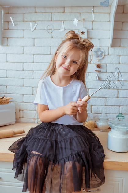 linda menina caucasiana com cabelo comprido e camiseta branca cozinhando na cozinha