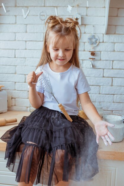 linda menina caucasiana com cabelo comprido e camiseta branca cozinhando na cozinha