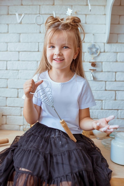 linda menina caucasiana com cabelo comprido e camiseta branca cozinhando na cozinha