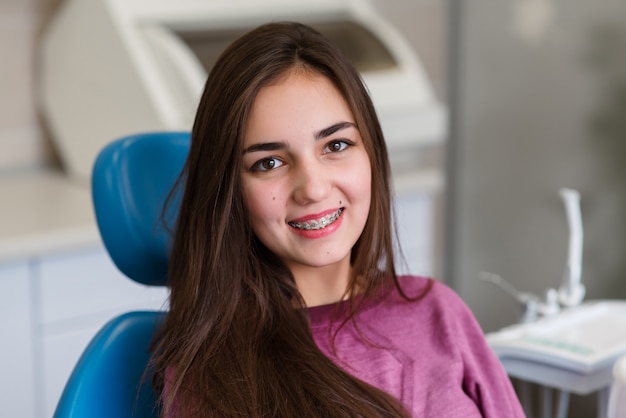 Linda menina com aparelho sorri em Odontologia