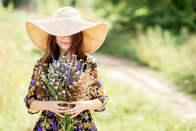 Linda menina com chapéu com um buquê de flores brancas e lilás