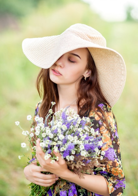 Linda menina com chapéu com um buquê de flores brancas e lilás