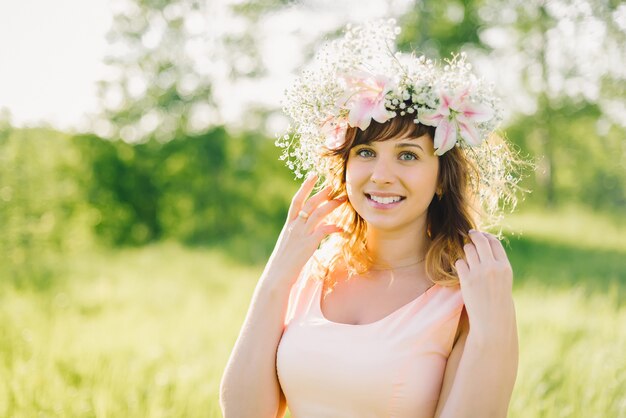 Linda menina com uma coroa de flores na cabeça, sorrindo ao ar livre em um dia ensolarado