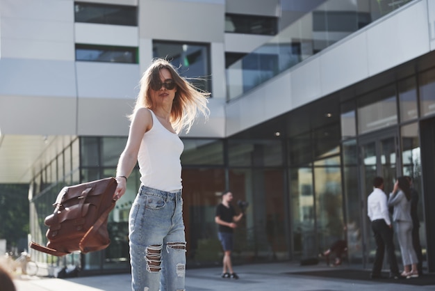 Linda menina com uma mochila, andando pela rua da cidade em uma manhã ensolarada