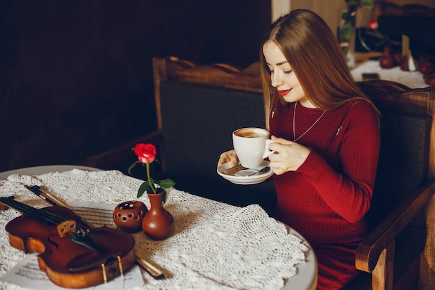 linda menina elegante, sentado em um café com violino e beber café