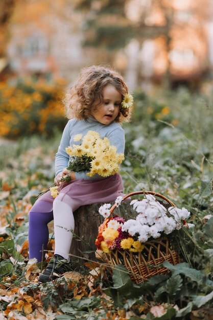 linda menina encaracolada na camisa azul no parque com flores no outono cartão de saúde outono