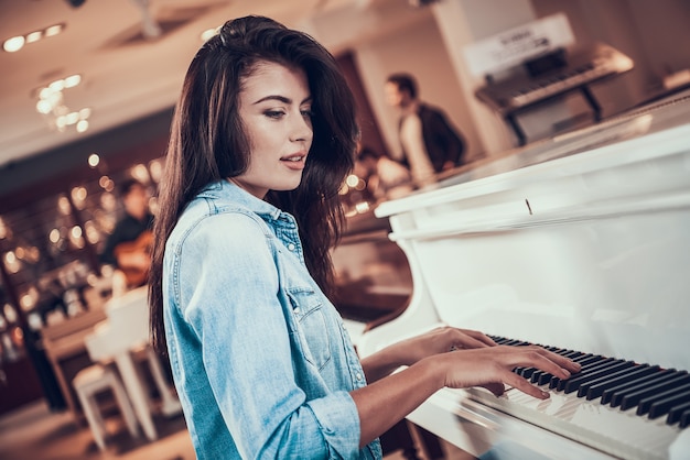 Linda menina está tocando piano na loja de música