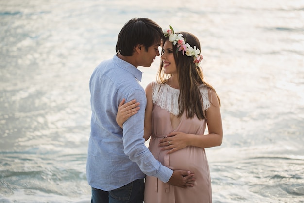 Linda menina grávida e homem na praia