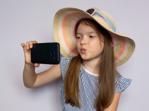 linda menina linda em um vestido e chapéu tira fotos faz selfie com um smartphone