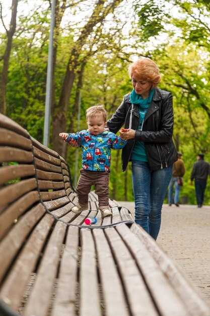 Linda menina mãe com um filho menino no parque no parque está sentado em um banco