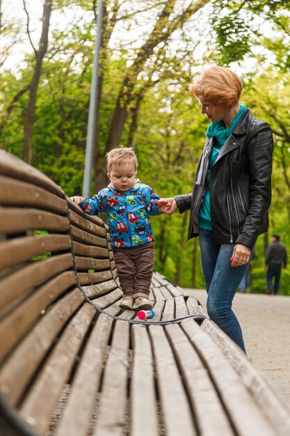 Linda menina mãe com um filho menino no parque no parque está sentado em um banco