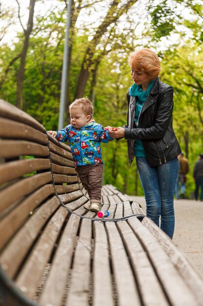 Linda menina mãe com um filho menino no parque no parque está sentado em um banco