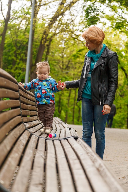 Linda menina mãe com um filho menino no parque no parque está sentado em um banco