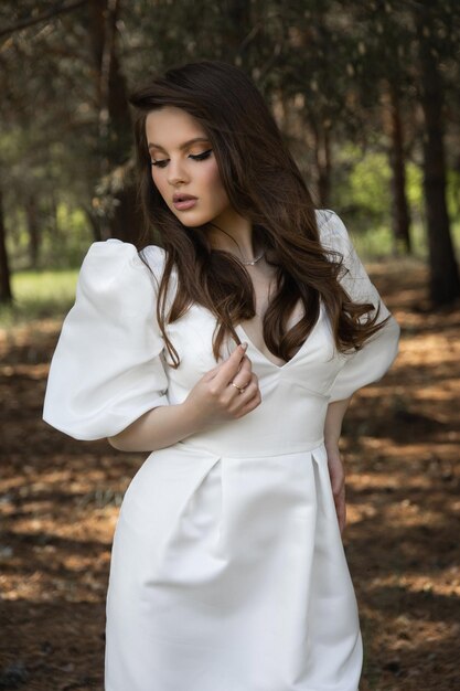 Foto linda menina morena caucasiana em um vestido de noiva na floresta