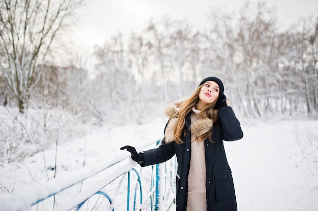 Linda menina morena com roupas quentes de inverno. Modelo com casaco de inverno e chapéu preto.