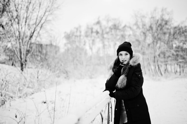 Linda menina morena com roupas quentes de inverno. Modelo com casaco de inverno e chapéu preto.