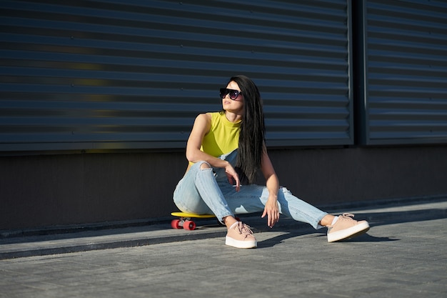 Linda menina morena elegante com cabelos longos em óculos de sol da moda vestindo blusa amarela