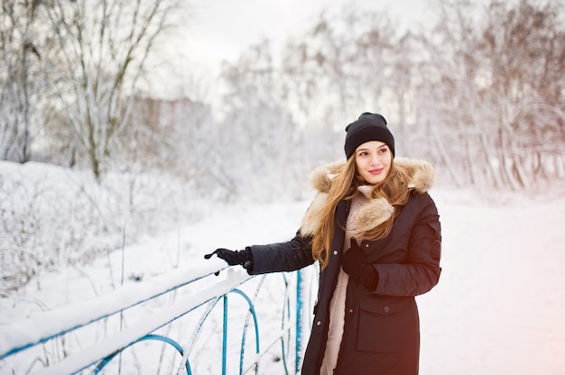 Linda menina morena em roupas quentes de inverno. Modelo de casaco de inverno e chapéu preto.