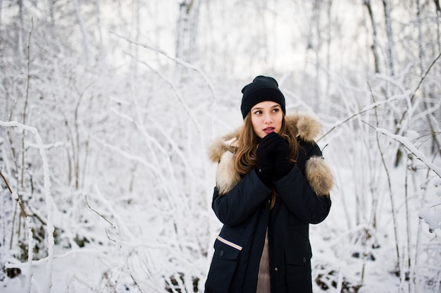 Linda menina morena em roupas quentes de inverno. modelo de casaco de inverno e chapéu preto.